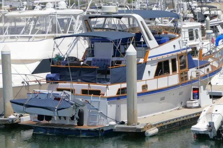 Slide: The Image of 1983 CHB 45 yacht docked at marina, featuring blue canopy and wooden accents. - 81