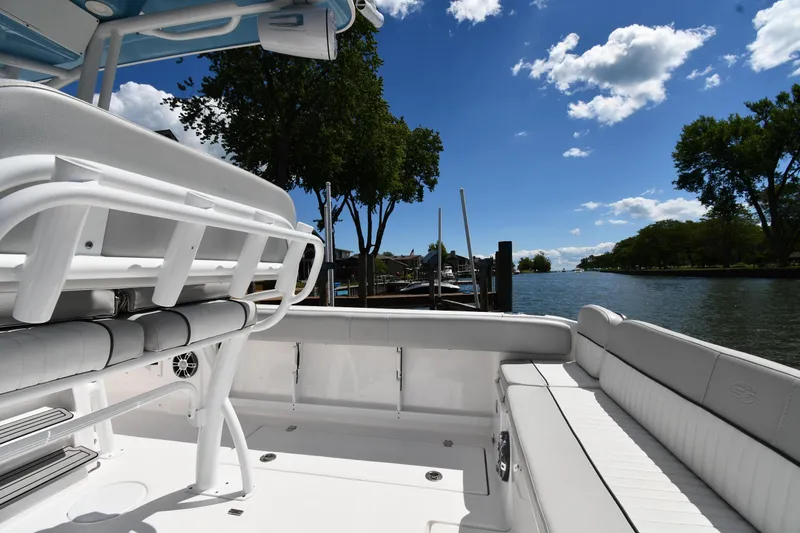 Slide: The Image of 2022 Sea Fox 268 Commander boat interior with white seating, docked by a scenic river. - 21