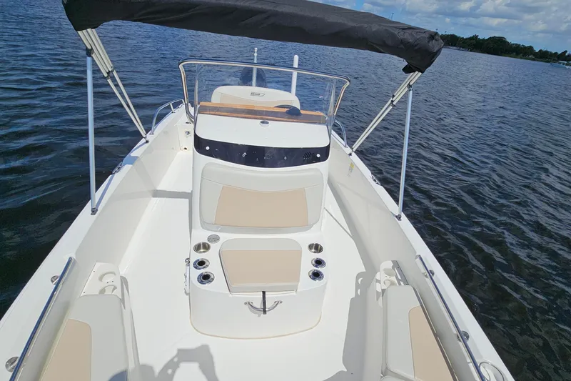 Slide: The Image of 2018 Boston Whaler 210 Dauntless boat on water, featuring seating and canopy. - 23