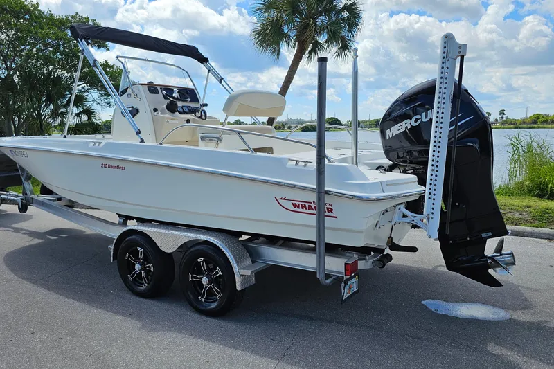 Slide: The Image of 2018 Boston Whaler 210 Dauntless boat on trailer, parked near a scenic waterfront. - 3