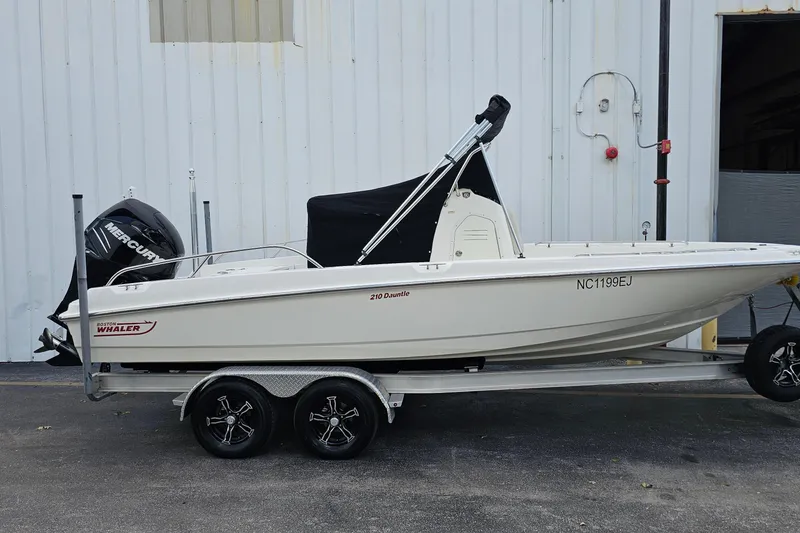 Slide: The Image of 2018 Boston Whaler 210 Dauntless boat on trailer, parked near a building. - 48
