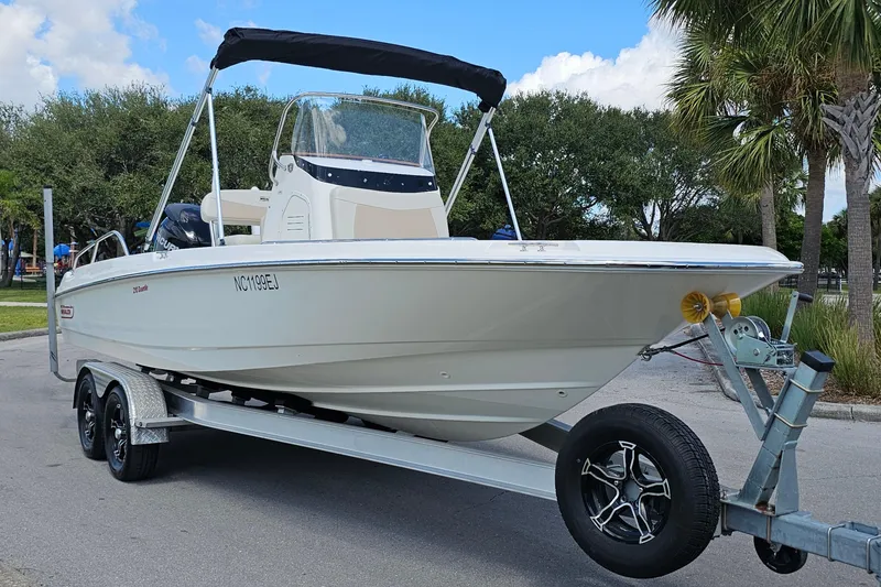 Slide: The Image of 2018 Boston Whaler 210 Dauntless boat on trailer, parked near palm trees. - 8