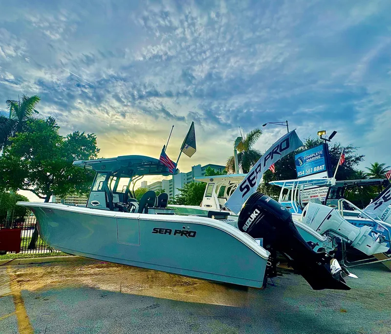 Slide: The Image of 2026 Sea Pro 292 DLX boat displayed outdoors with flags and palm trees. - 0