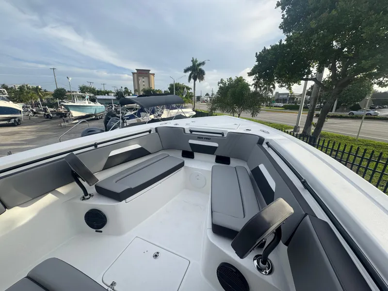 Slide: The Image of 2026 Sea Pro 292 DLX boat interior with seating and speakers, parked outdoors. - 21