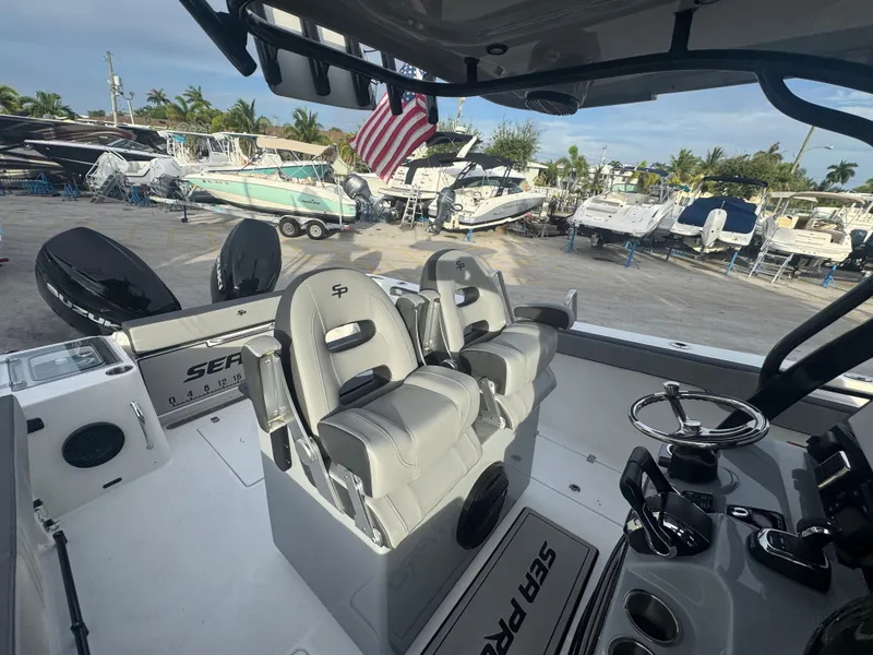 Slide: The Image of 2026 Sea Pro 292 DLX boat interior with dual seats and steering wheel, docked at marina. - 24