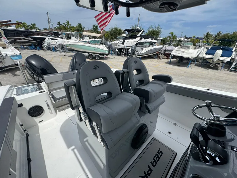 Slide: The Image of 2026 Sea Pro 292 DLX boat interior with dual seats and steering wheel, docked among other boats. - 37