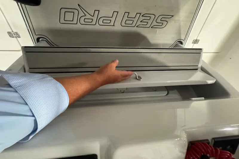 Slide: The Image of Hand opening storage compartment on 2026 Sea Pro 332 DLX boat. - 38