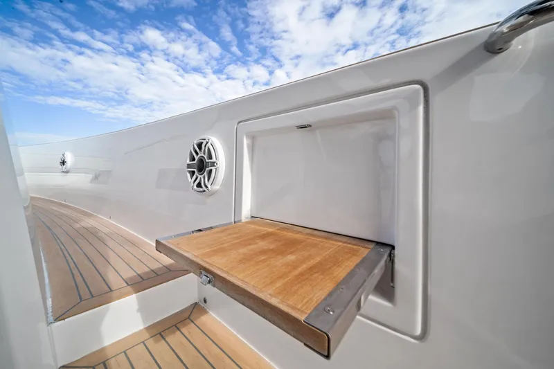 Slide: The Image of 2024 Pardo Yachts P43 deck with wooden fold-out table and speakers under blue sky. - 39