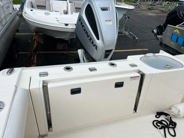 Slide: The Image of 2021 Cobia 237 Center Console with Honda outboard motor, featuring rod holders and storage. - 10