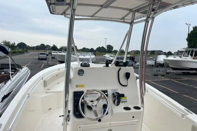 Slide: The Image of 2021 Cobia 237 Center Console boat with steering wheel and controls, parked in a marina. - 4