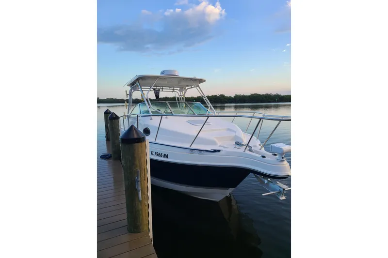 The Image of 2005 Aquasport 275 Explorer boat docked on calm water at sunset. - 0