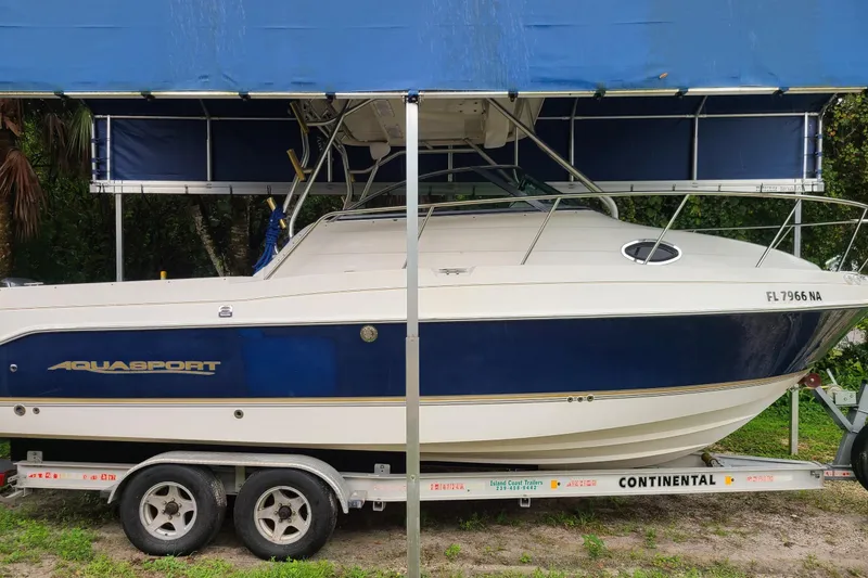 Slide: The Image of 2005 Aquasport 275 Explorer boat on trailer under blue canopy. - 2