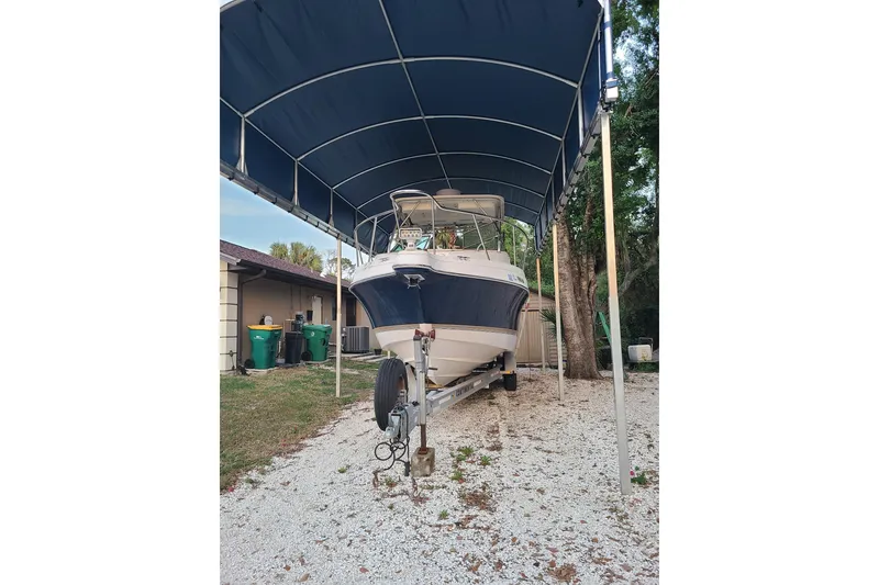 Slide: The Image of 2005 Aquasport 275 Explorer boat under a canopy on a gravel driveway. - 3