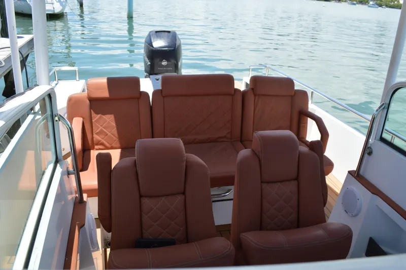 Slide: The Image of 2015 Axopar T-Top boat interior with brown leather seating, docked on calm water. - 19
