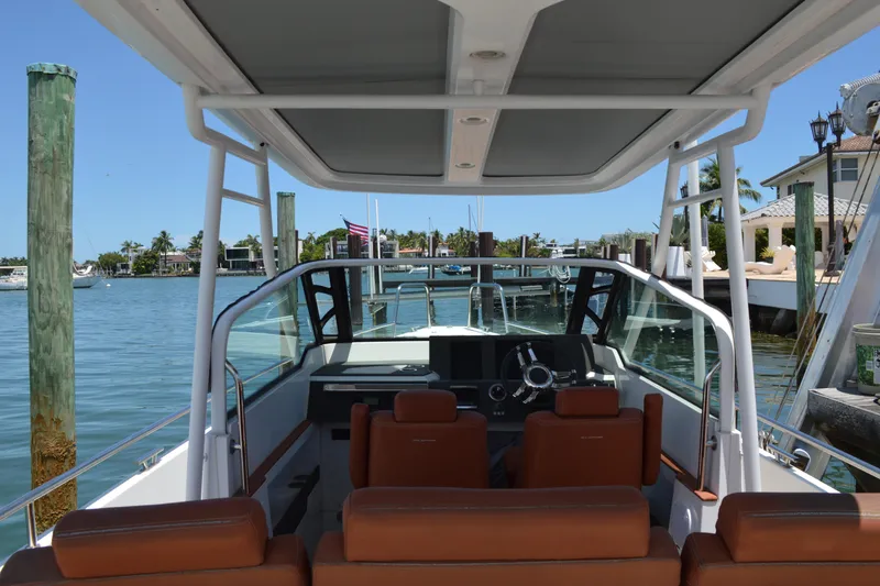 Slide: The Image of 2015 Axopar T-Top boat interior with steering wheel, docked by waterfront homes. - 20