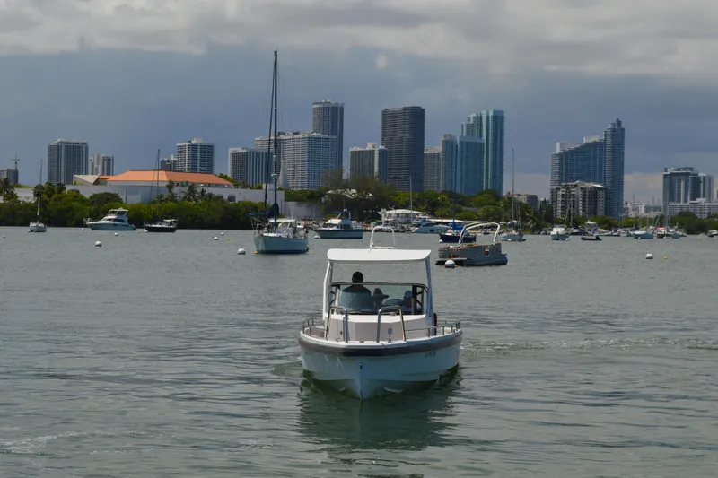 Slide: The Image of 2015 Axopar T-Top boat cruising in urban harbor with city skyline backdrop. - 3