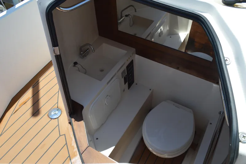 Slide: The Image of 2015 Axopar T-Top boat interior with compact bathroom and wooden flooring. - 34