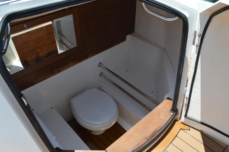 Slide: The Image of 2015 Axopar T-Top boat interior with compact toilet and wooden accents. - 35