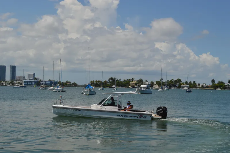 Slide: The Image of 2015 Axopar T-Top boat cruising in a scenic bay with sailboats and city skyline. - 4
