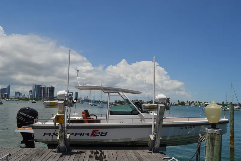 Slide: The Image of 2015 Axopar T-Top boat docked with city skyline and blue sky background. - 5