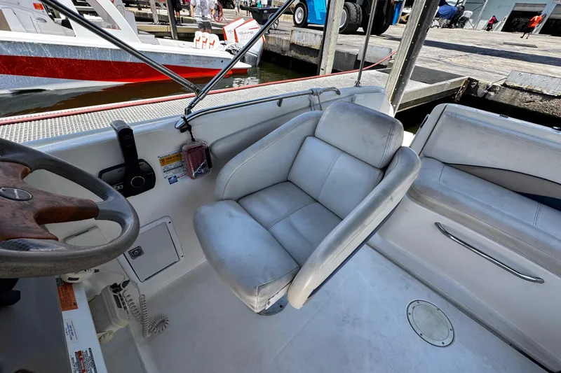 Slide: The Image of 2000 Chaparral Sunesta 232 boat interior with steering wheel and seating at dock. - 18