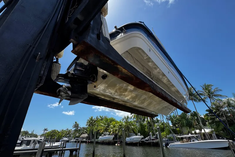 Slide: The Image of 2000 Chaparral Sunesta 232 boat lifted at marina, clear sky, palm trees in background. - 34