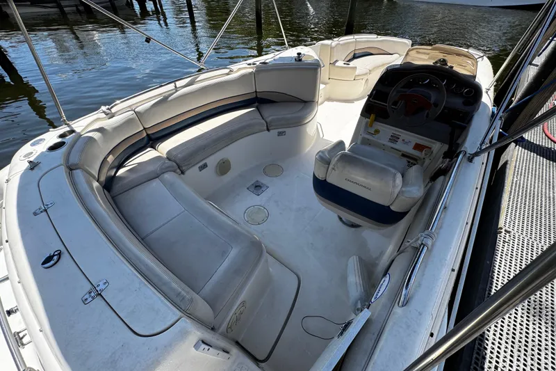 Slide: The Image of 2000 Chaparral Sunesta 232 boat interior with seating and steering wheel, docked by the water. - 9
