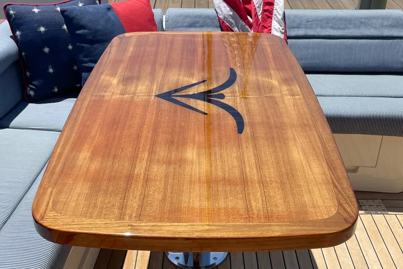 Slide: The Image of Elegant wooden table on 2017 Hinckley Talaria 43 Motoryacht, surrounded by striped cushions. - 4