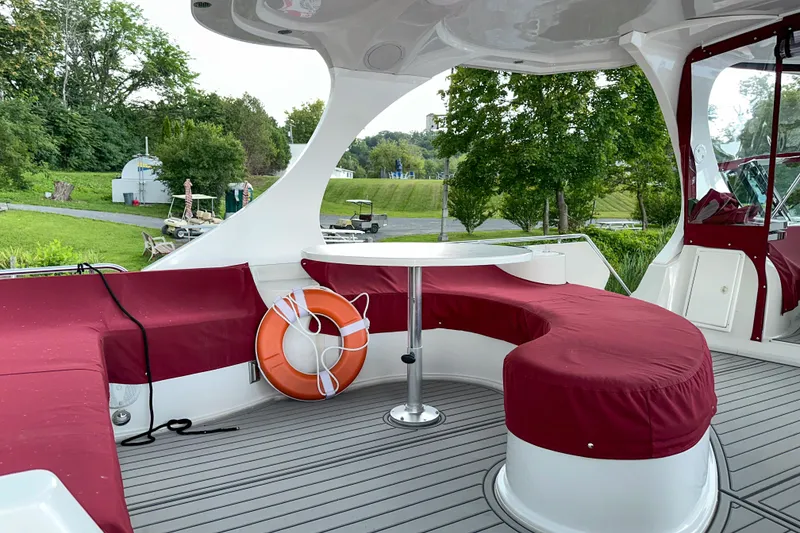Slide: The Image of Luxury 2012 Bluewater 5200 yacht deck with red seating and table, surrounded by greenery. - 19