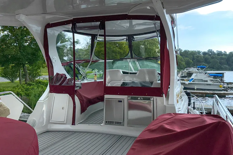 Slide: The Image of 2012 Bluewater 5200 boat interior with red covers, docked near lush greenery. - 20