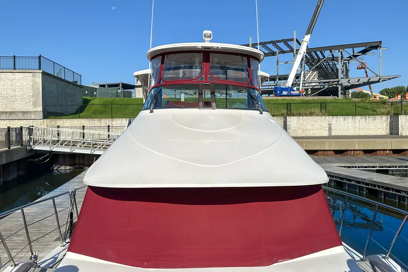 Slide: The Image of 2012 Bluewater 5200 yacht docked, featuring red and white exterior, with construction in background. - 3