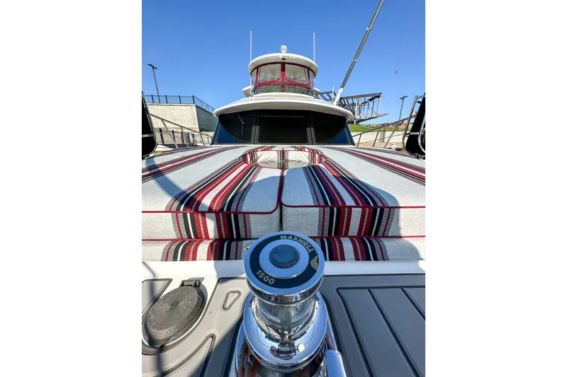 Slide: The Image of 2012 Bluewater 5200 yacht with striped deck cushions and winch, under clear blue sky. - 4