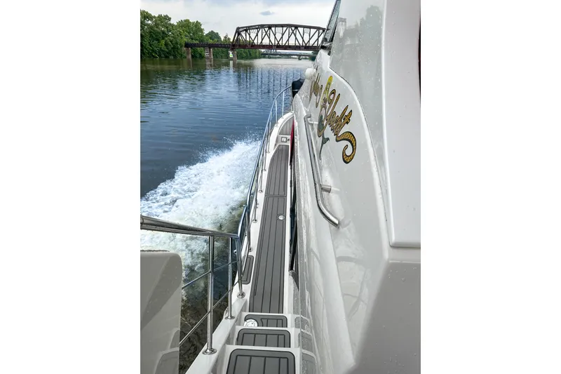 Slide: The Image of 2012 Bluewater 5200 yacht cruising on a river near a bridge. - 7
