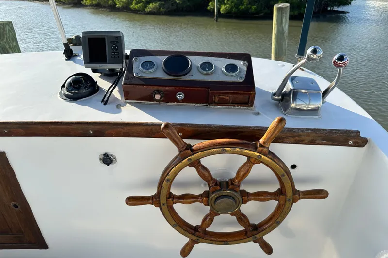 Slide: The Image of 1973 CHB 34 boat helm with wooden wheel, gauges, and controls by the water. - 12