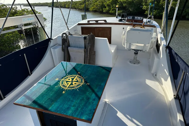 Slide: The Image of 1973 CHB 34 boat interior with compass-themed table, steering wheel, and river view. - 15