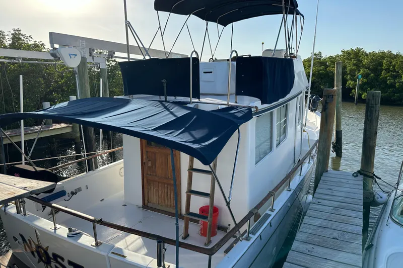 Slide: The Image of 1973 CHB 34 boat docked, featuring blue canopy and wooden door, surrounded by water. - 16