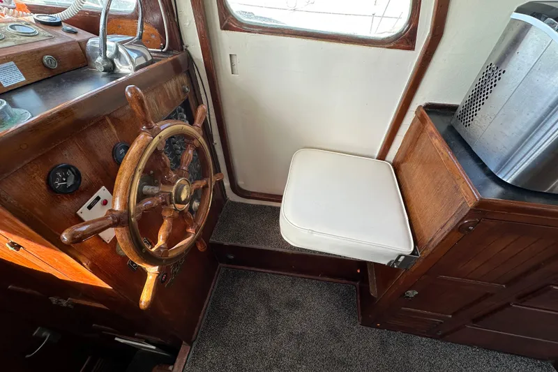 Slide: The Image of 1973 CHB 34 boat interior with wooden steering wheel and white cushioned seat. - 22