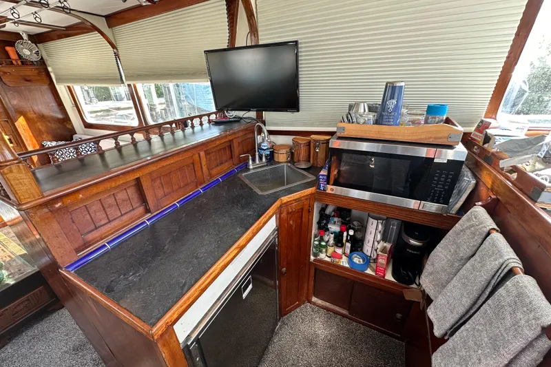 Slide: The Image of 1973 CHB 34 boat interior with kitchenette, featuring a sink, microwave, and wooden cabinetry. - 26