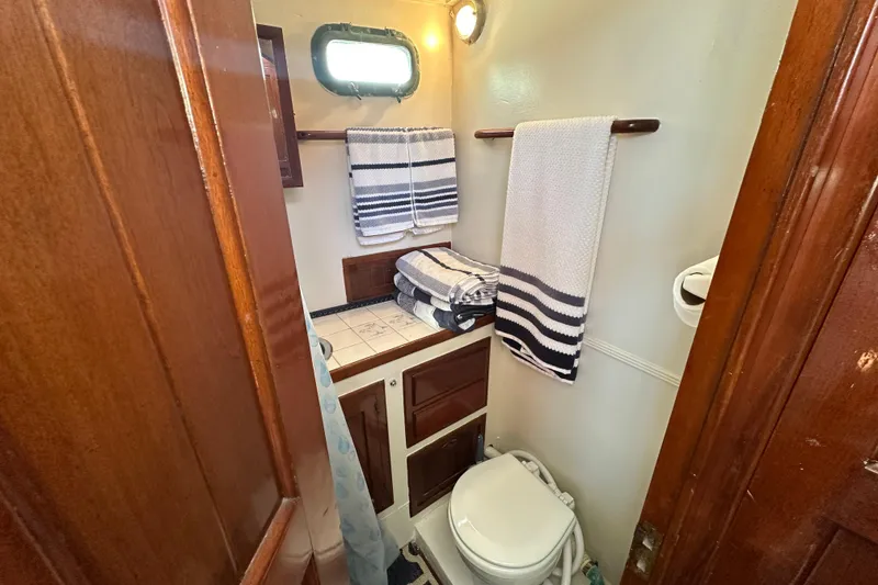 Slide: The Image of 1973 CHB 34 boat bathroom with wooden cabinets, striped towels, and a small window. - 31