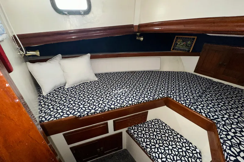 Slide: The Image of 1973 CHB 34 boat cabin with patterned bedding, wooden accents, and cozy pillows. - 36