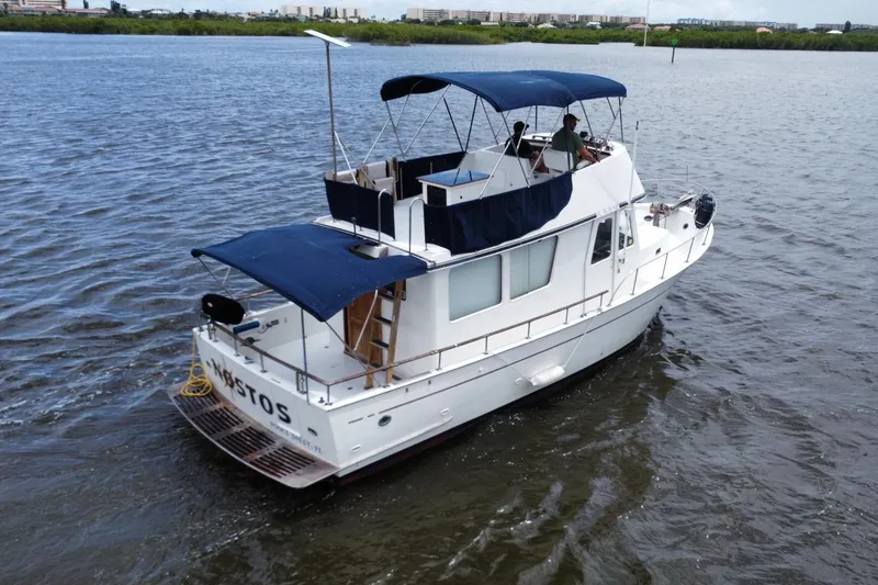 Slide: The Image of 1973 CHB 34 boat cruising on a calm river with blue canopy and visible deck. - 4