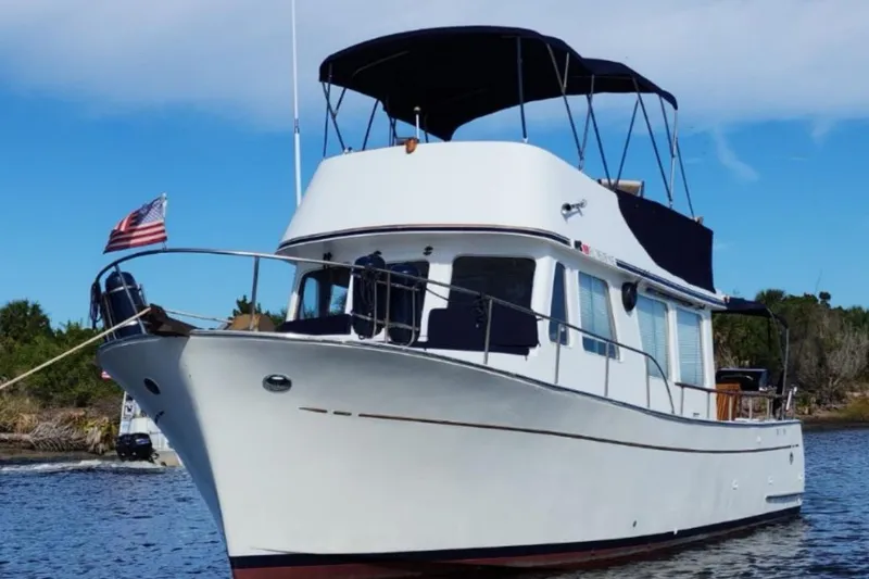 The Image of 1973 CHB 34 boat with American flag, cruising on a calm waterway under blue skies. - 0