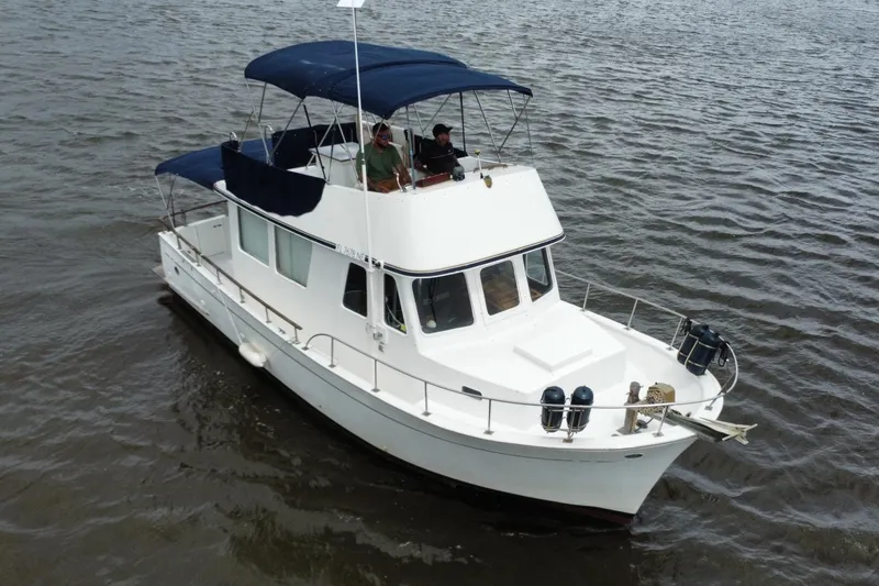 Slide: The Image of 1973 CHB 34 boat cruising on water with blue canopy and white hull. - 6