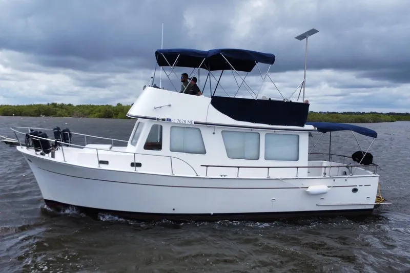 Slide: The Image of 1973 CHB 34 boat cruising on a cloudy day, featuring a white hull and blue canopy. - 1