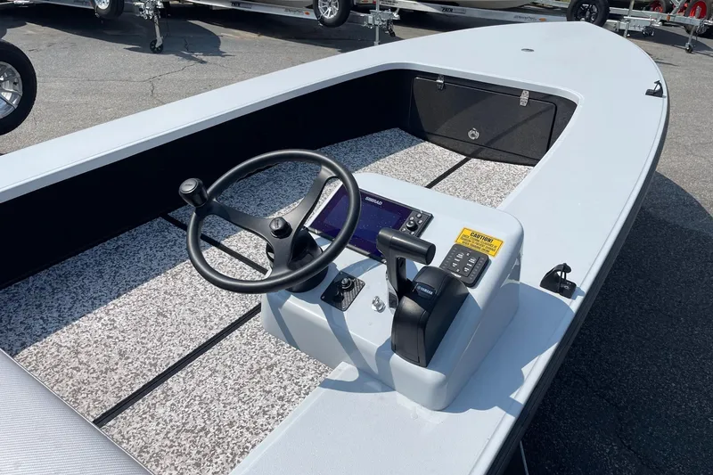 Slide: The Image of 2025 Chittum Skiffs Challenger 18 boat interior with steering console and motor, displayed outdoors. - 7