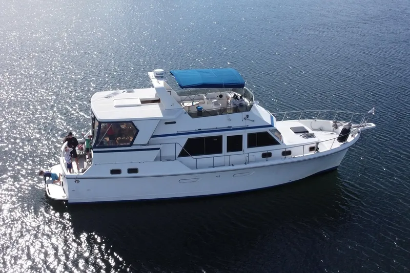 Slide: The Image of 1986 Ponderosa 47 yacht with blue canopy cruising on sparkling water. - 0