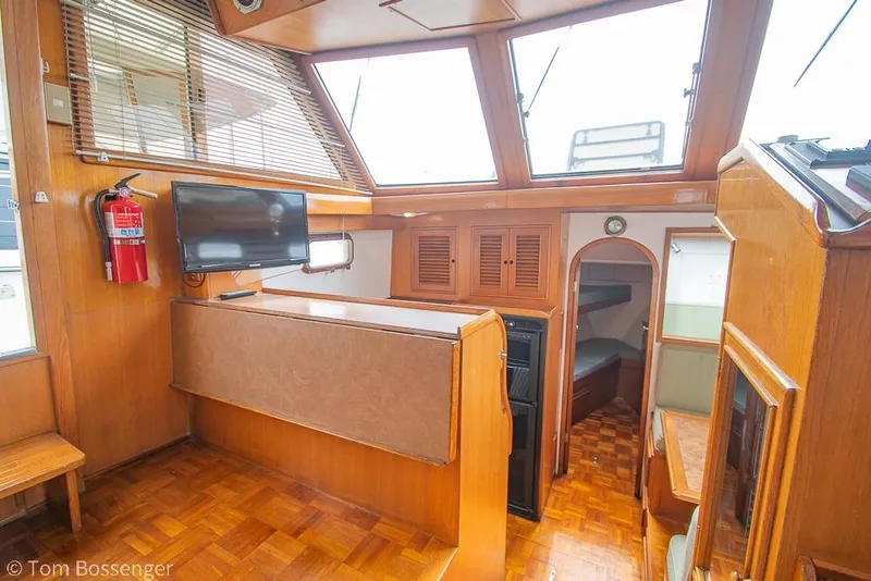 Slide: The Image of 1986 Ponderosa 47 yacht interior with wood paneling, TV, and cozy cabin space. - 11