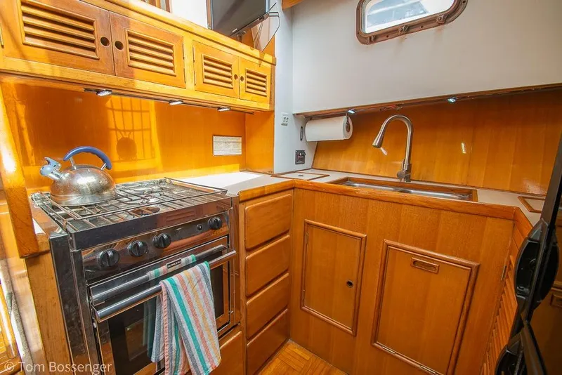 Slide: The Image of 1986 Ponderosa 47 yacht kitchen with wooden cabinets, stove, and sink. - 15