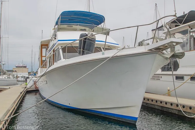 Slide: The Image of 1986 Ponderosa 47 yacht docked at marina, featuring blue accents and spacious deck. - 2