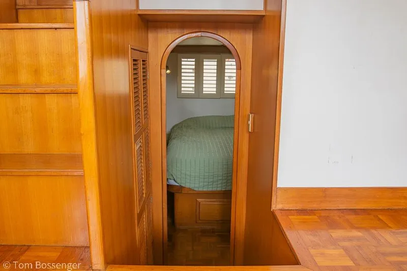 Slide: The Image of Wood-paneled interior of 1986 Ponderosa 47 yacht, featuring a cozy bedroom with green bedding. - 20